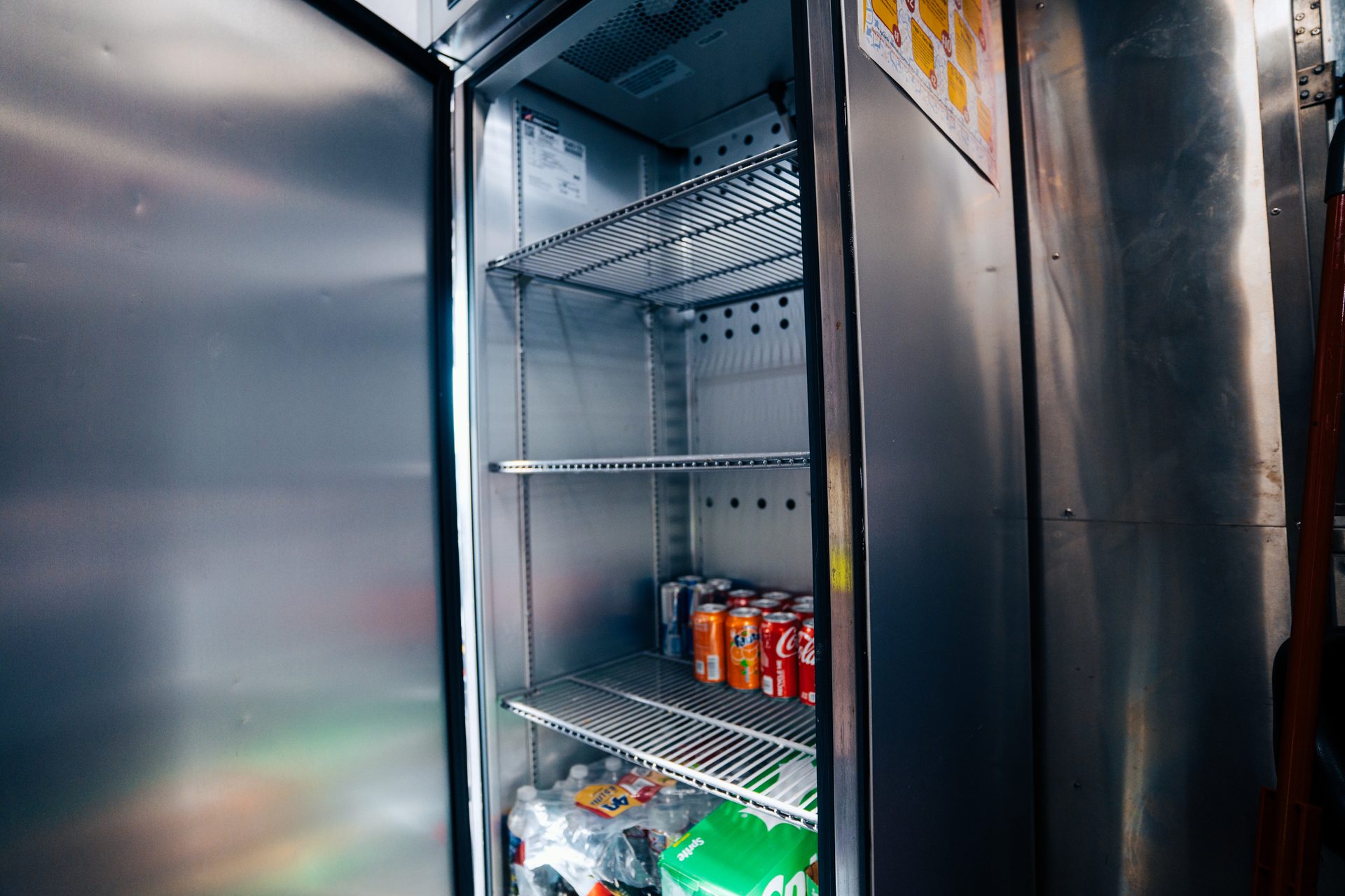 Open refrigerator stocked with canned and bottled drinks